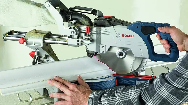 Person using a BOSCH GCM18V-08N 8-1/2" Single-Bevel Slide Miter Saw to cut a white board