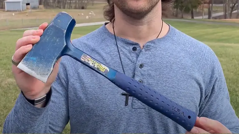 Person in blue shirt holding a Wilton Tools 8 lb. Head - 36” B.A.S.H Splitting Maul with blue head and handle in a grassy field