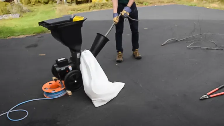 Person operating a Patriot 1.5 HP Electric Wood Chipper Leaf Shredder on a driveway