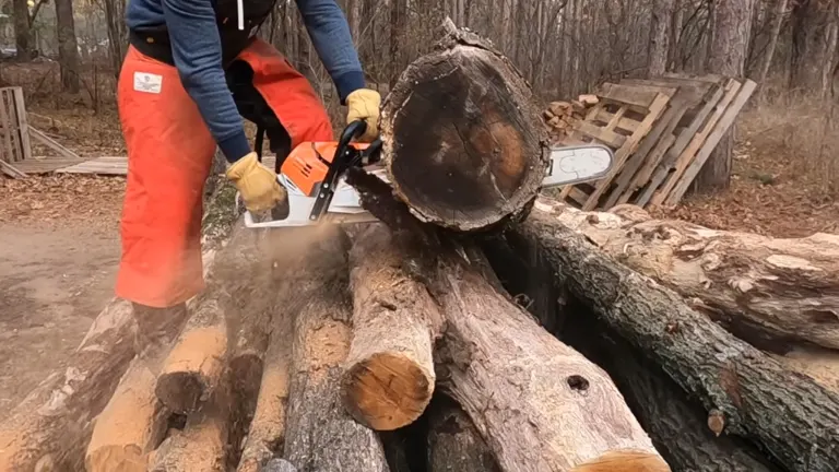 a person, wearing safety gear, using a Stihl MS 500i chainsaw to cut through a large log