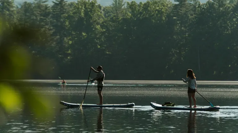 two individuals paddleboarding on a serene lake in Pisgah National Forest