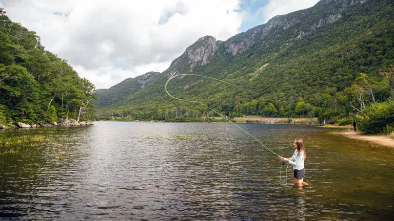 A person fly fishing in a serene lake at Franconia Notch State Park