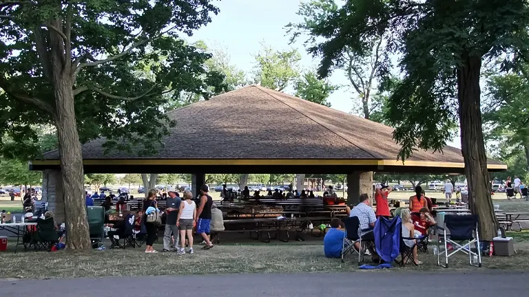 People gathering at a covered picnic area surrounded by trees in Niagara Falls State Park