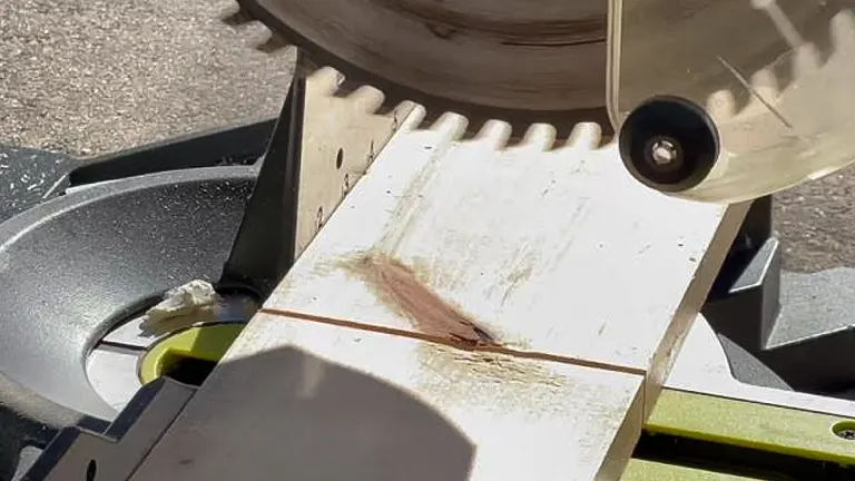 Close-up of a miter saw making an angled cut on a stained wooden board
