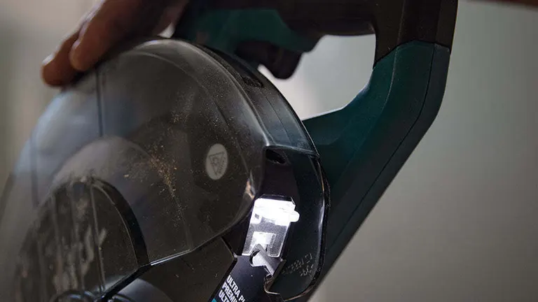 Close-up of the green and black handle and clear blade guard of a Makita 40V Max XGT 8-1/2” Dual-Bevel Sliding Compound Miter Saw in use
