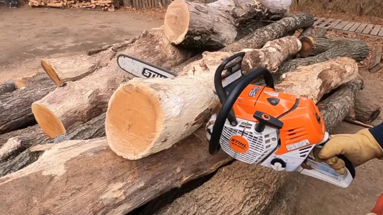 a person, visible by their hand wearing a yellow glove, operating a Stihl MS 500i chainsaw