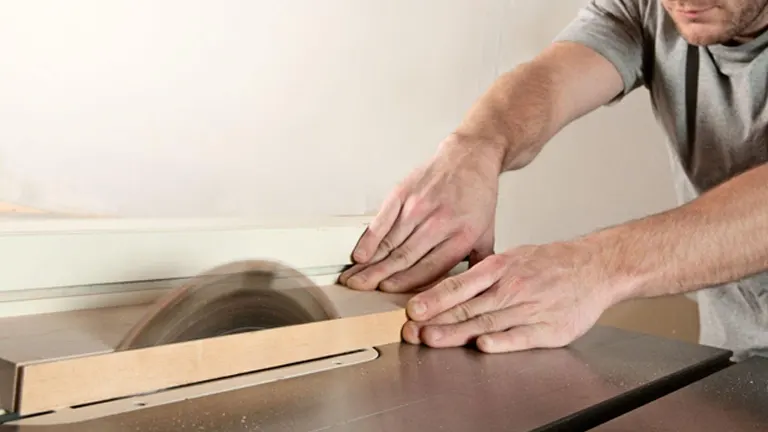 Person’s hands operating a table saw to cut a piece of wood