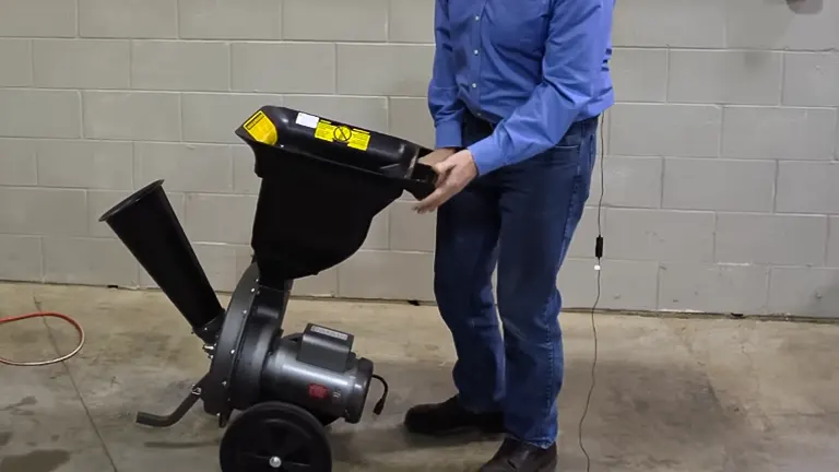 Person in a blue shirt demonstrating the use of a Patriot 1.5 HP Electric Wood Chipper Leaf Shredder indoors
