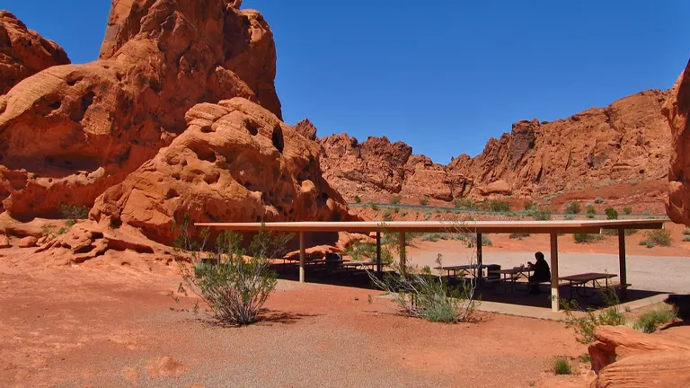 Red rock formations under a clear blue sky at Valley of Fire State Park with a shaded viewing area