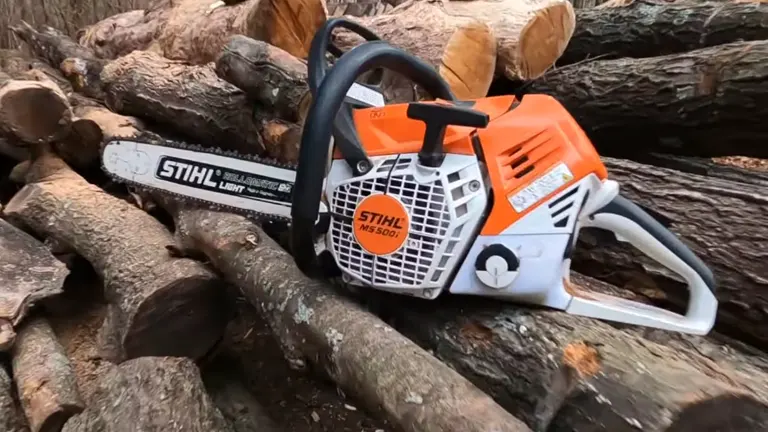 Stihl MS 500i chainsaw with an orange and white body, placed on top of a pile of freshly cut brown logs