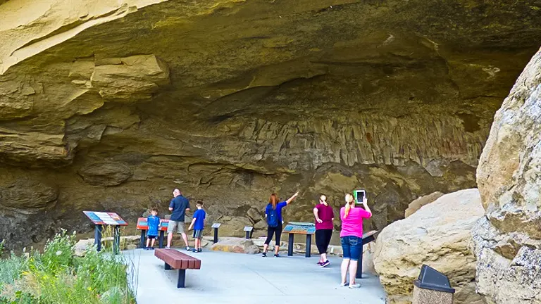 Visitors observing cave walls at Pictograph Cave State Park