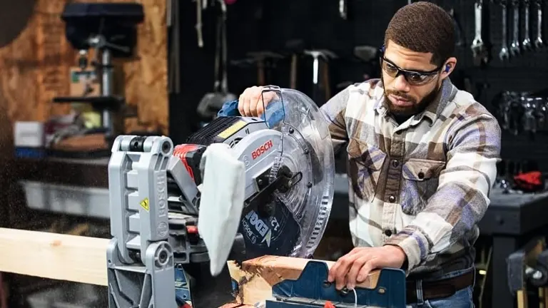 Person operating a BOSCH PROFACTOR 18V 12" Dual-Bevel Glide Miter Saw to cut wood in a well-equipped workshop