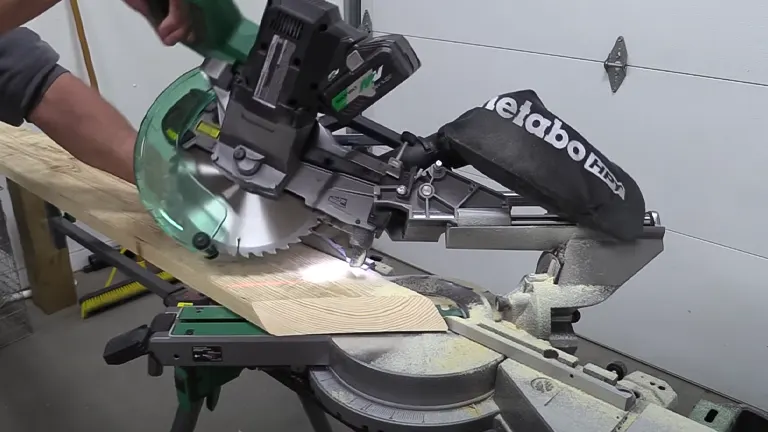Person operating a Metabo HPT 36V MultiVolt 10” Dual-Bevel Sliding Miter Saw to cut wood in a workshop
