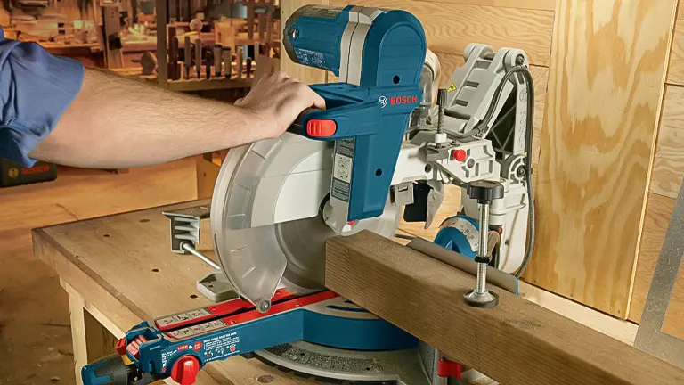 Person using a BOSCH GCM12SD 12” Dual-Bevel Sliding Miter Saw to cut wood in a workshop