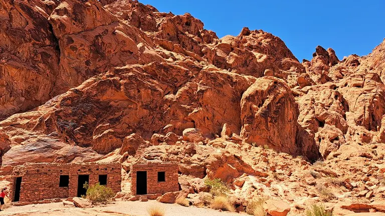 Stone cabins nestled against rugged red rock formations under a clear blue sky at Valley of Fire State Park