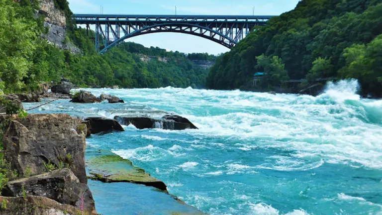 Rapid turquoise waters of Niagara River with a bridge spanning across at Niagara Falls State Park
