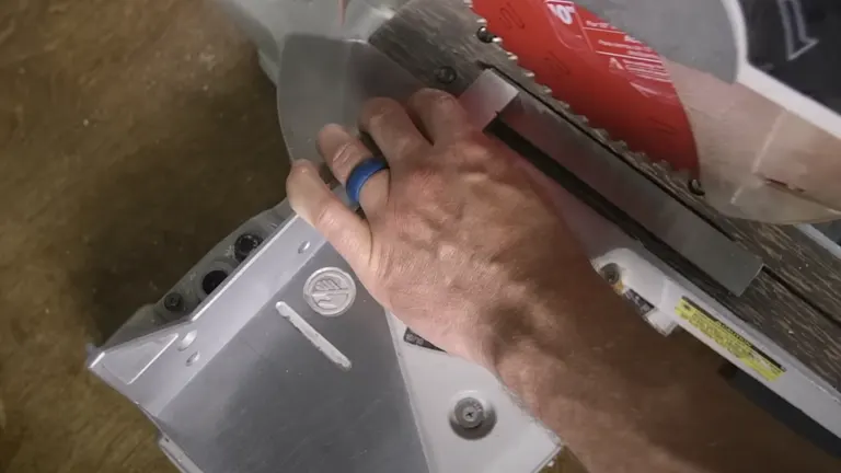 Hand adjusting red miter saw on wooden workbench for accurate cuts