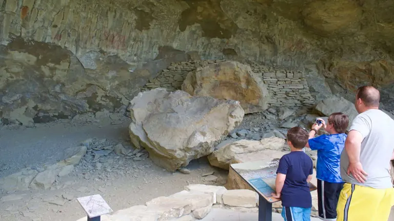 Visitors observing historic cave paintings at Pictograph Cave State Park