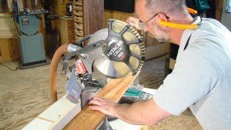 Person in safety gear adjusting Hitachi miter saw for precise cuts
