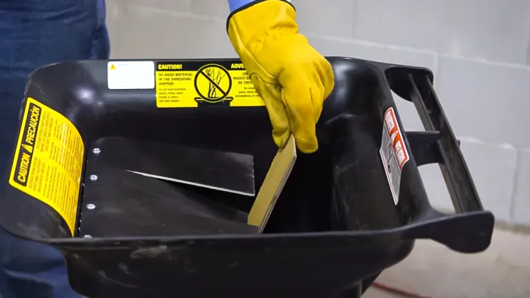 Person in yellow gloves cleaning the interior of a Patriot 1.5 HP Electric Wood Chipper Leaf Shredder