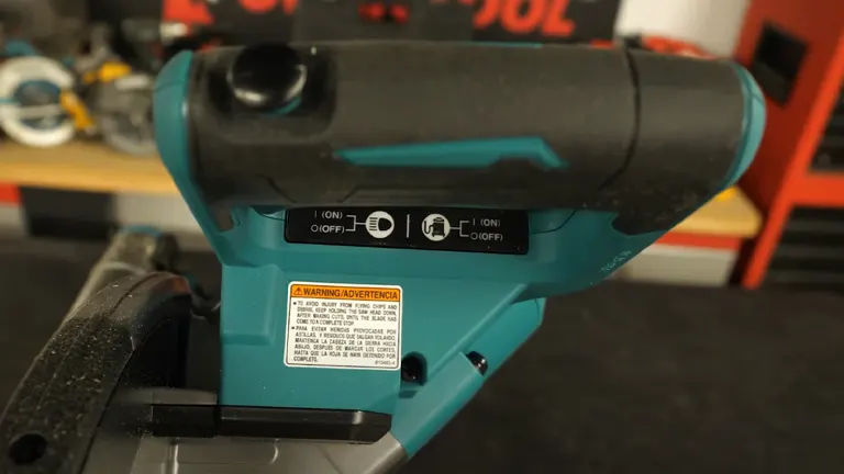 Close up of the handle and warning label of a Makita 40V Max XGT 10” Dual-Bevel Sliding Compound Miter Saw