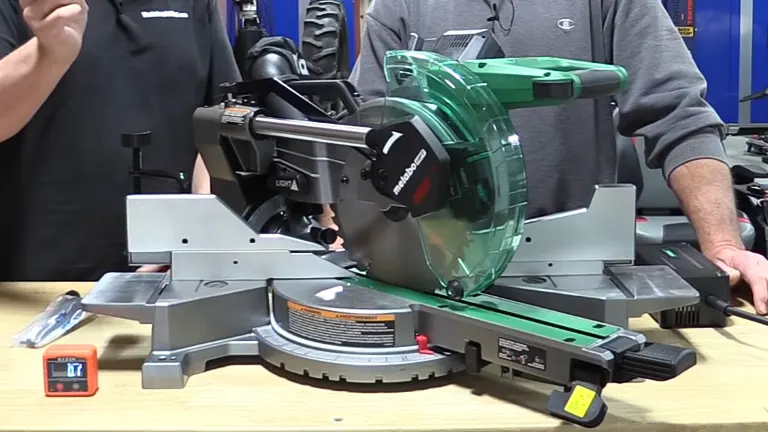 Two people operating a Metabo HPT 36V MultiVolt 10” Dual-Bevel Sliding Miter Saw on a workbench