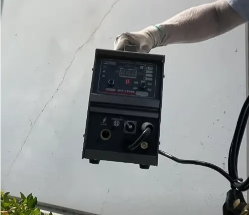 Hand in a white glove adjusting the settings on an AMICO MIG-160 Flux Stick TIG Arc 3-in-1 Welder