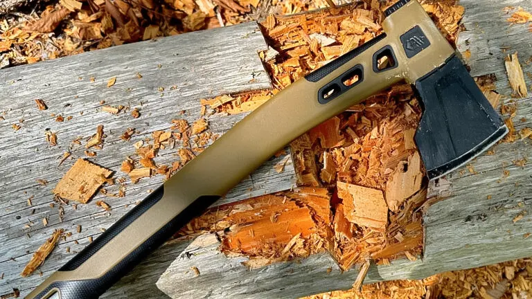 Modern camping hatchet with a tan and black handle resting on a chopped piece of wood