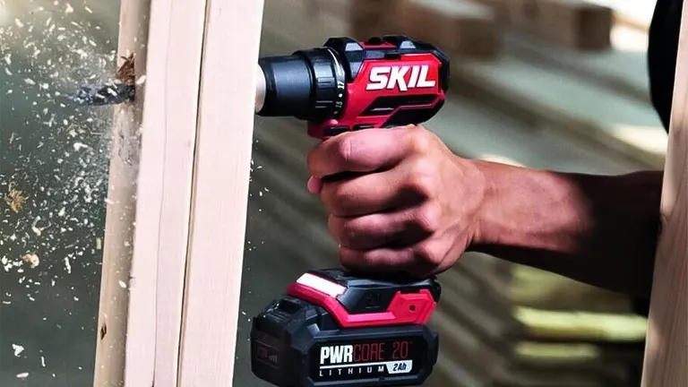 A person using a Skil PWR Core 20 Compact Brushless Drill Driver on a wooden surface