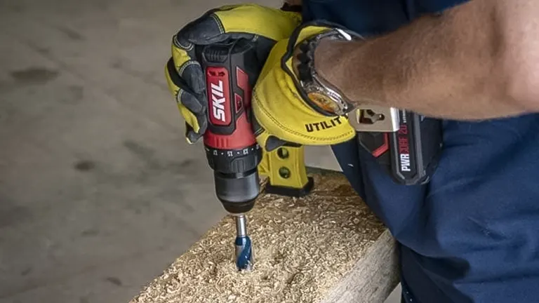 A person using a Skil PWR Core 20 Compact Brushless Drill Driver on a wooden surface