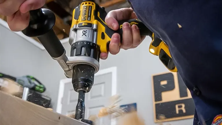A person using a DEWALT 20V MAX Hammer Drill to drill a hole in a wooden surface