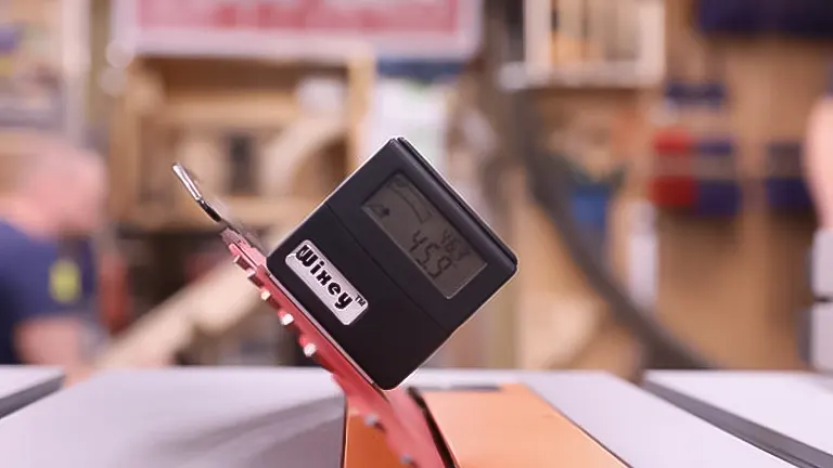 Digital angle gauge measuring a 45-degree stop on a table saw in a workshop