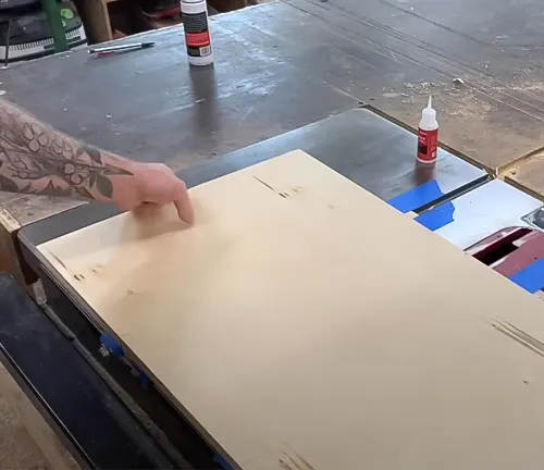 Hand pointing at wooden jig on table saw