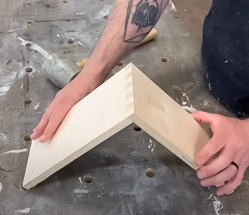 Hands holding wooden box joint jig on workbench