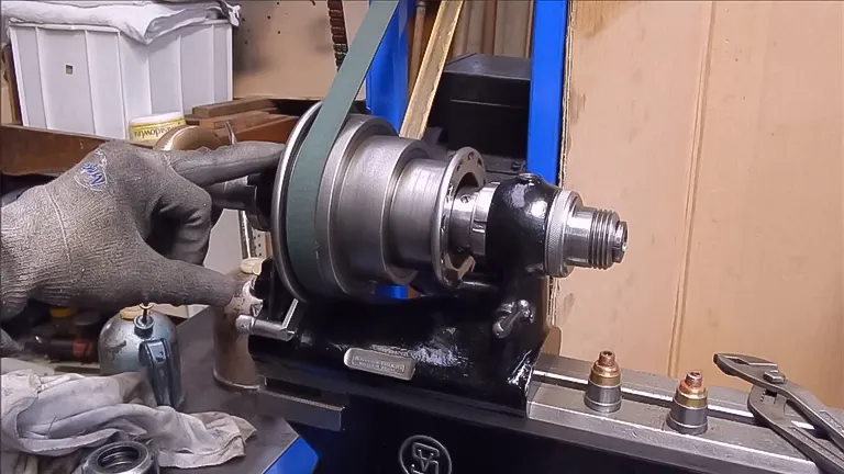 Gloved hand maintaining a wood lathe with a blue strap