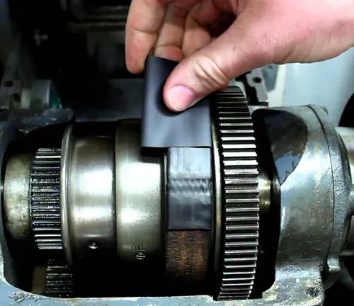 Hand using a brush to clean the gears of a wood lathe