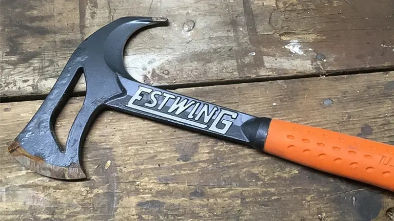ESTWING Forged Steel Hunter Hatchet with a distinct black steel head and an orange grip, lying on a wooden surface