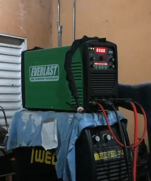 Everlast Power 185DV AC/DC TIG Stick Welder on a workbench, connected to cables, with a digital display