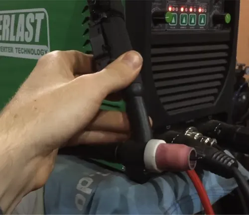 A person holding a TIG torch with an Everlast Power 185DV AC/DC TIG Stick Welder in the background
