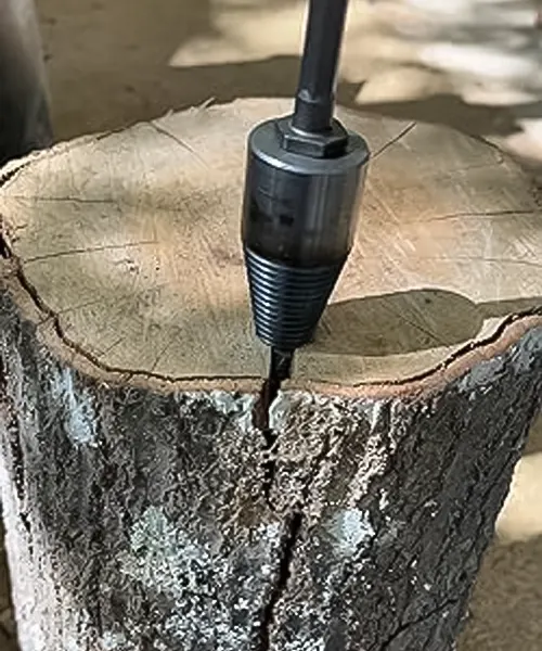 A Firewood Log Screw Splitter Drill Bit inserted into a log in an outdoor or workshop setting