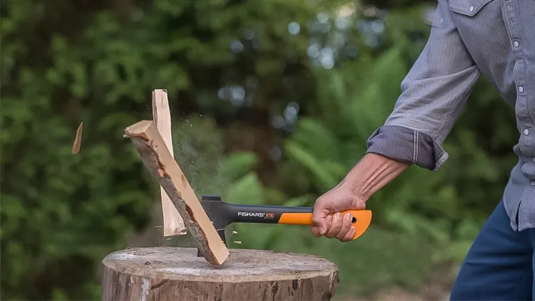 Person using a Fiskars X7 Hatchet to split wood on a stump