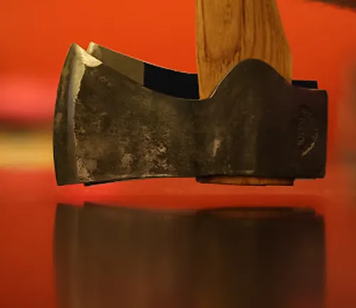 Close-up of a Garant Cougar Axe head with a wooden handle against a red background
