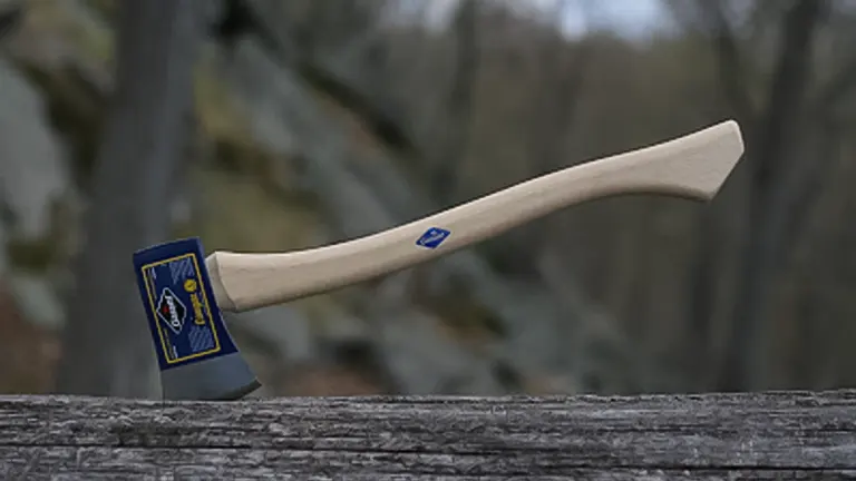 Garant Cougar Axe with a wooden handle and blue head, placed on a log in a forest setting
