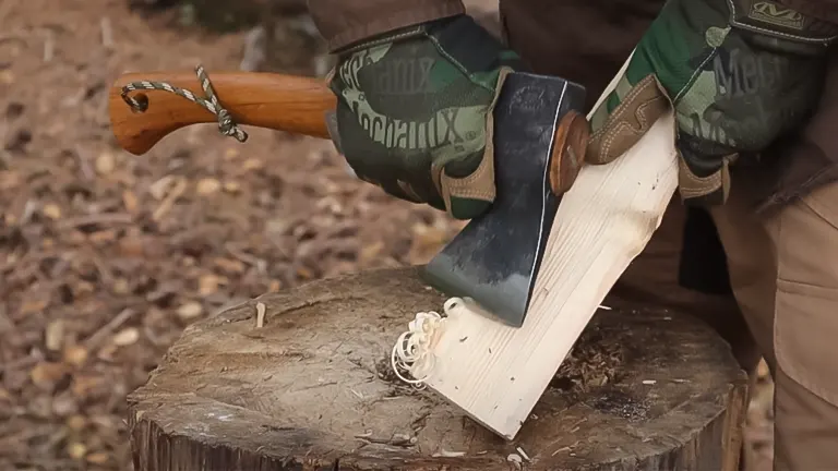 Person wearing gloves splitting wood with a Gransfors Bruks Wildlife Hatchet