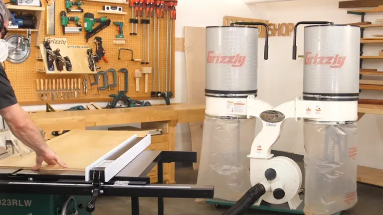 Person operating a table saw in a workshop with Grizzly 3 HP Dust Collectors functioning in the background