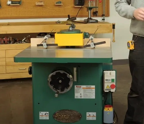 Grizzly Industrial 3 HP Shaper in a workshop with a person adjusting it
