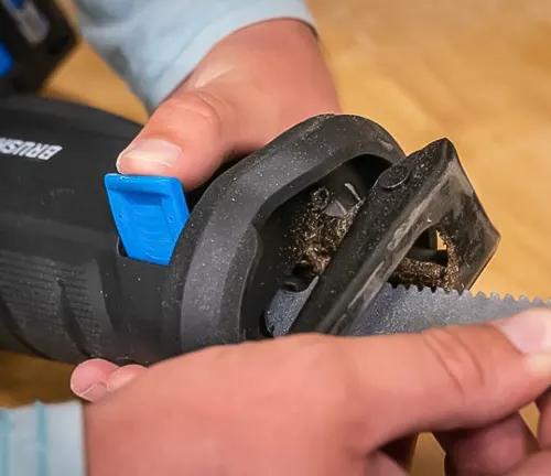 Person holding a HART 20-Volt Reciprocating Saw, focusing on the used blade area in a workshop setting