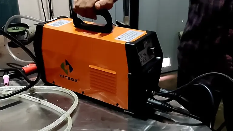 Person handling a HITBOX HBT2000 TIG ARC welding machine on a metal table