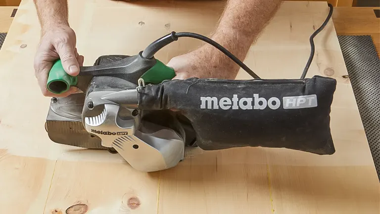 Person using a belt sander on a wooden floor