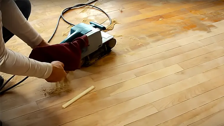 Person sanding a wood floor with a belt sander